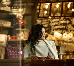 red lady dior bag on a table next to a lady having a coffee date